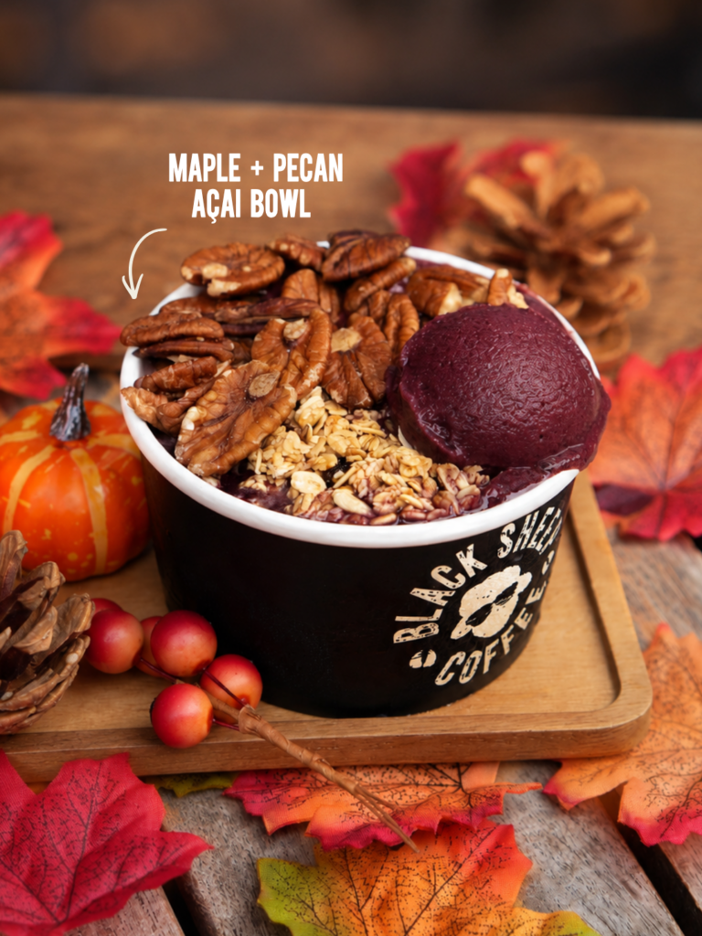 Black Sheep Coffee Maple and Pecan Açaí Bowl topped with pecans and granola surrounded by autumn decorations.