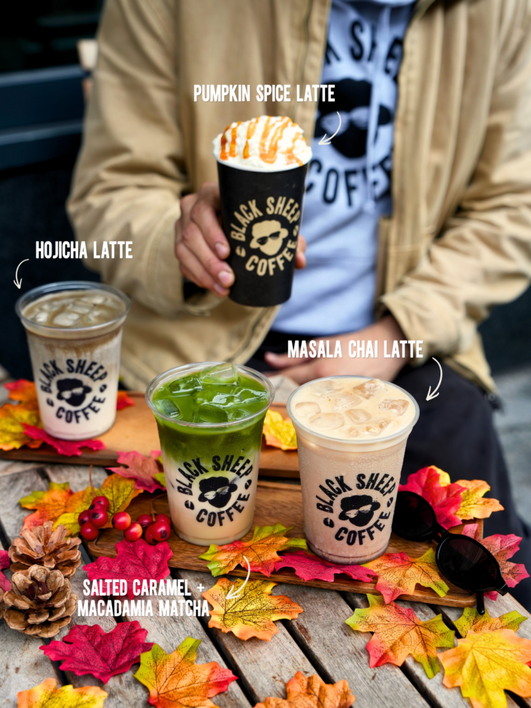 Black Sheep Coffee autumn drinks display featuring Pumpkin Spice Latte, Hojicha Latte, Salted Caramel Macadamia Matcha, and Masala Chai Latte set among colourful autumn leaves.